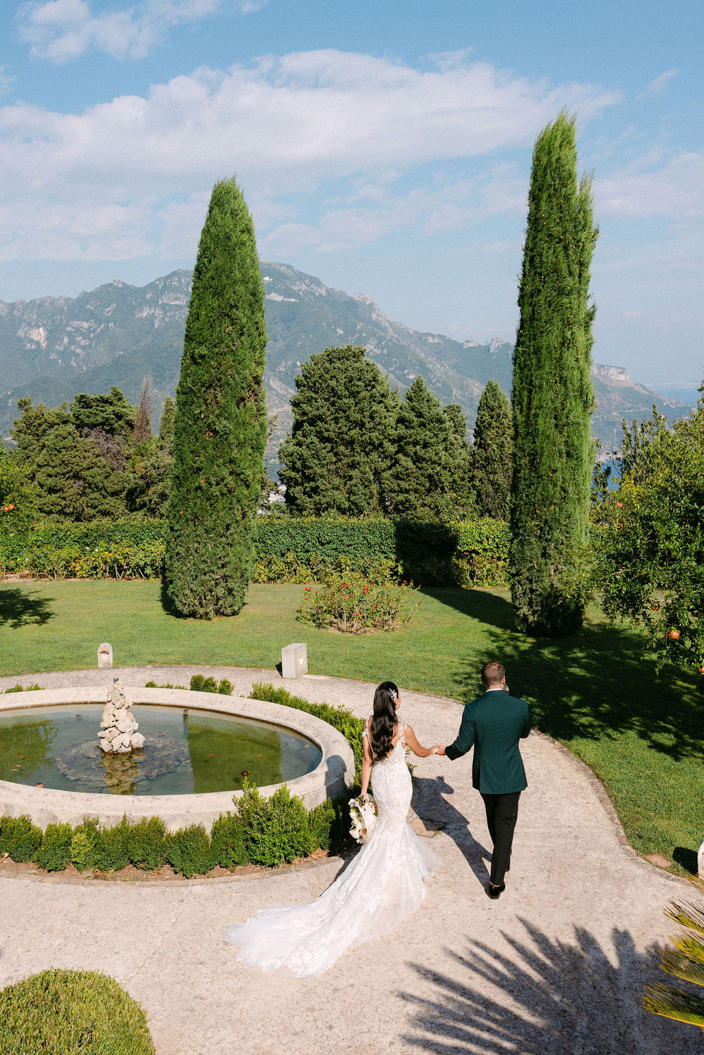 groom escorts bride through gardens at Villa Cimbrone wedding venue in Italy